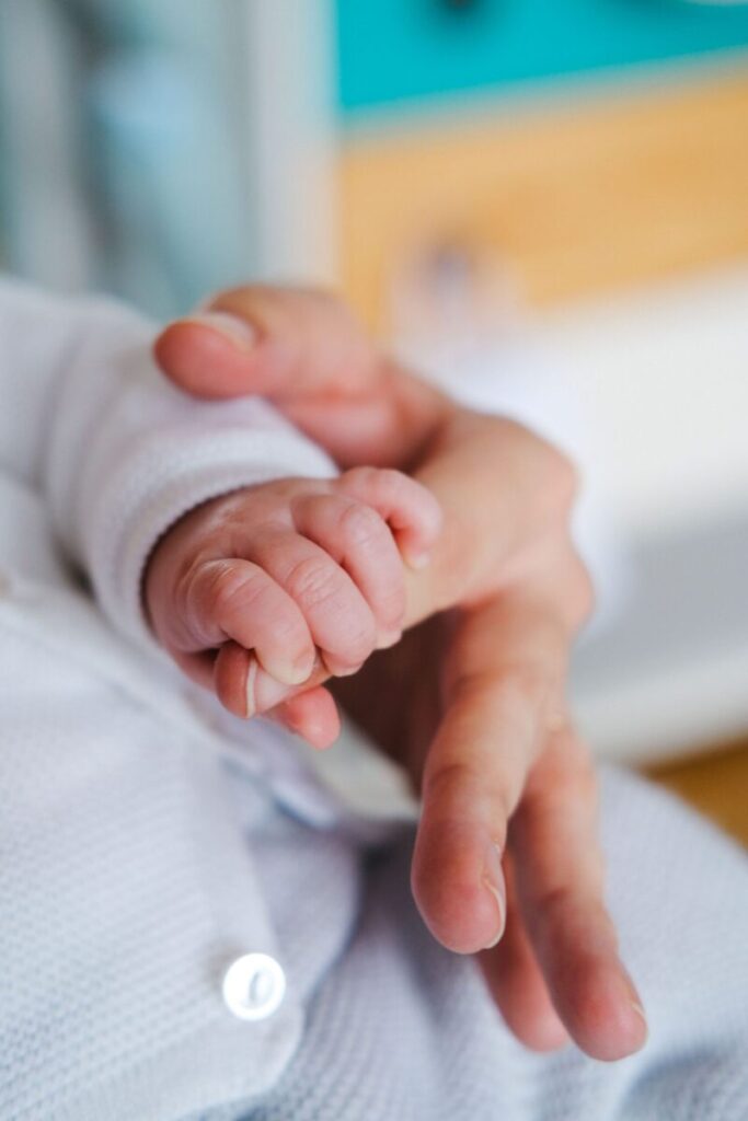 Tender moment of an adult and baby's hand, symbolizing love and care.