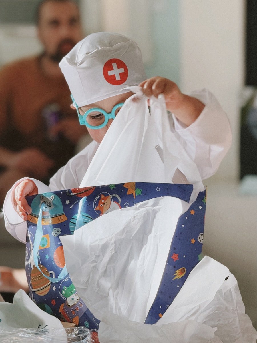 Child in doctor costume opening a gift bag.